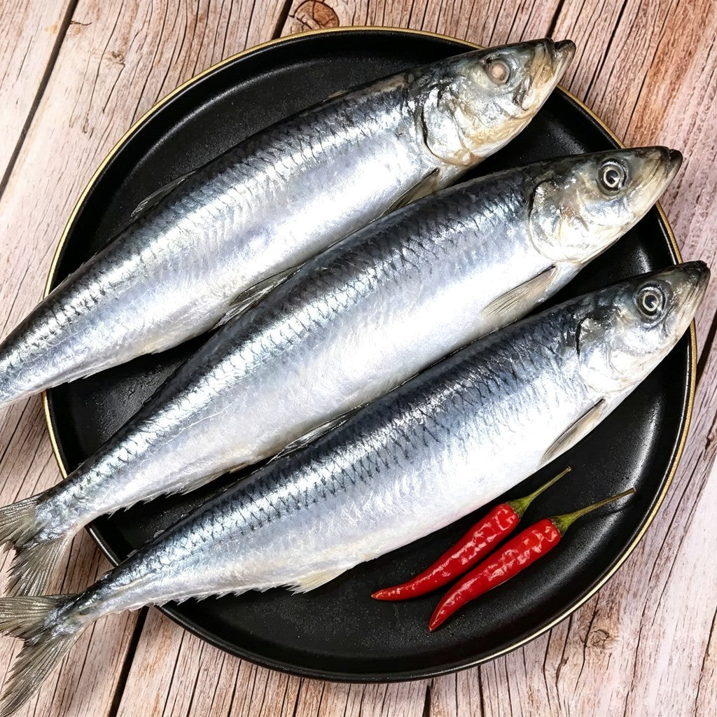Whole silver herring on a black plate
